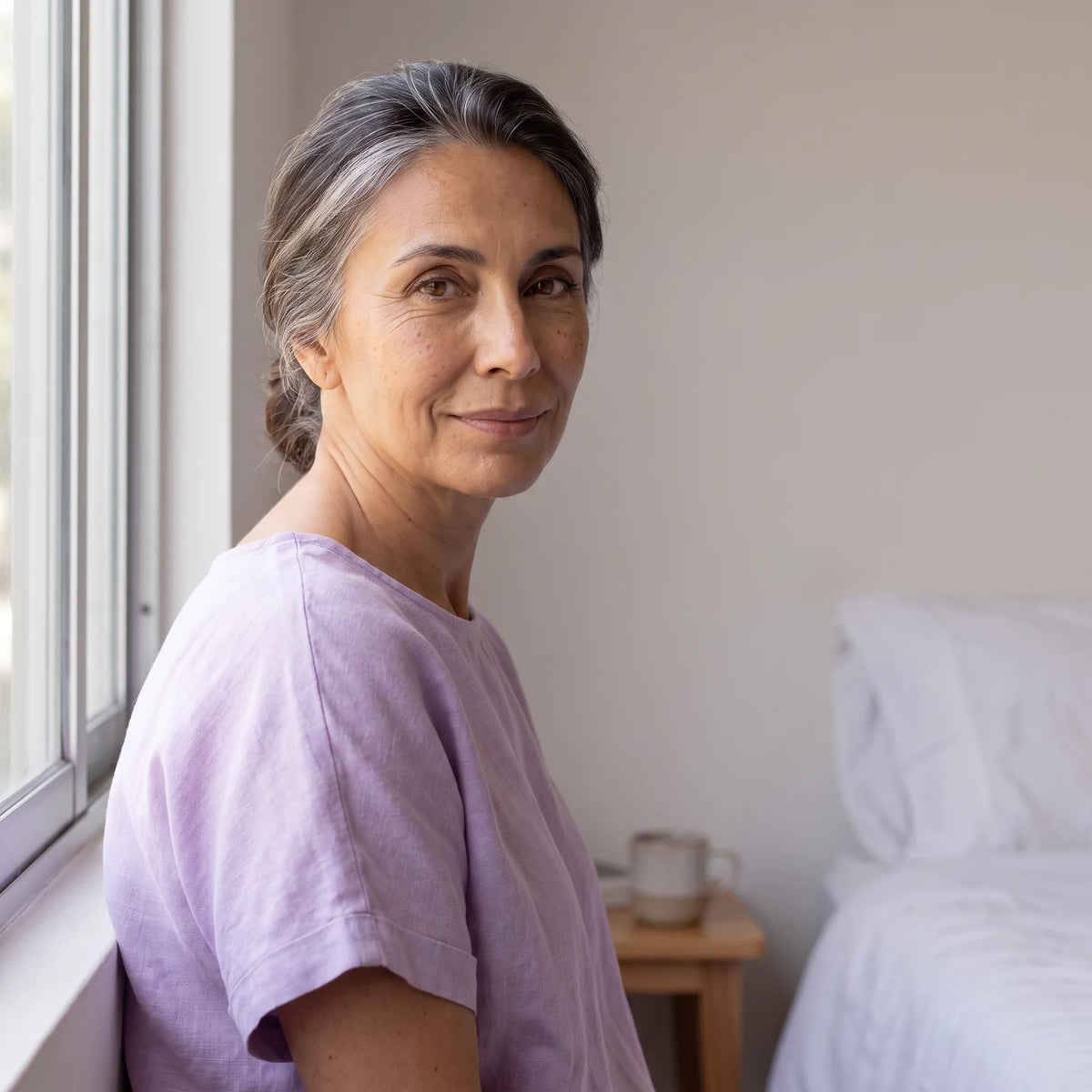 La misma mujer a la mañana siguiente junto a la ventana, con la piel descansada